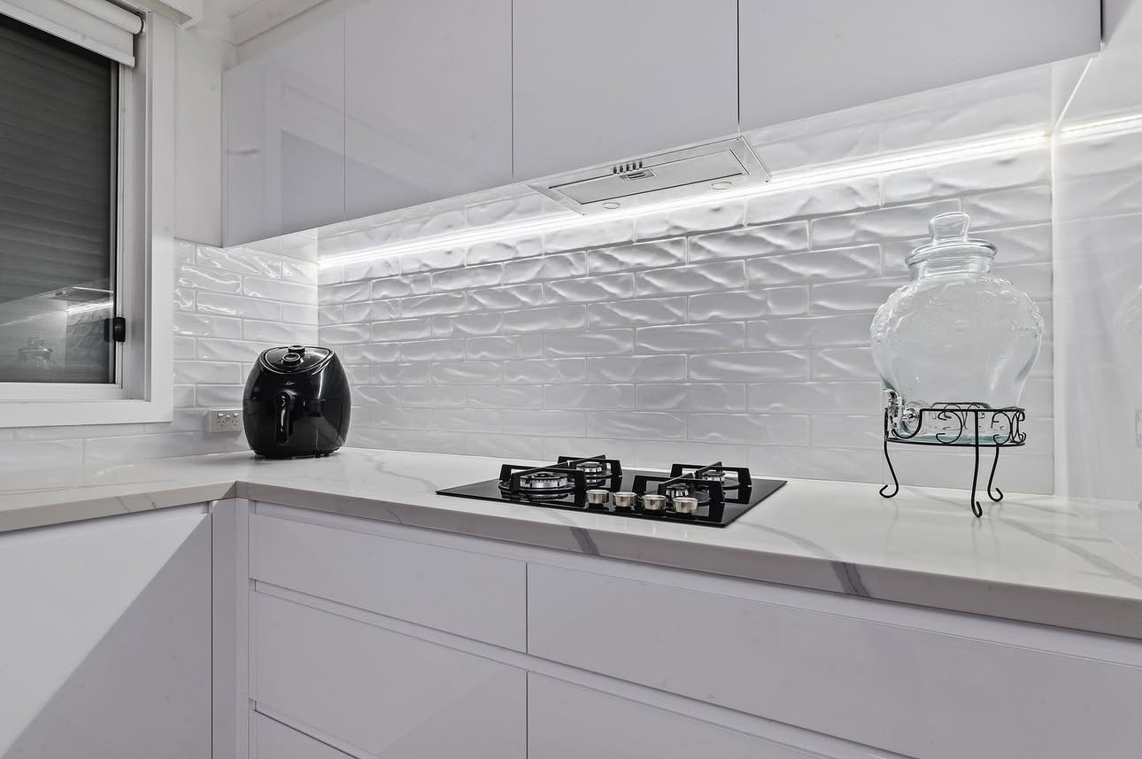 Marble benchtop kitchen with gas cooktop by PMD Projects