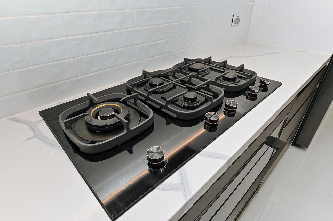 Black gas cooktop on white marble benchtop